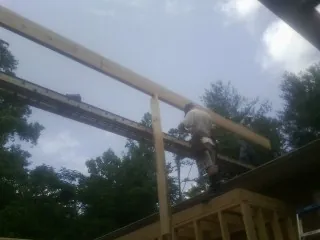 Carpenter setting a ridge beam over a new addition frame — Ice Dam Removal by Roofing Brothers in Glenville