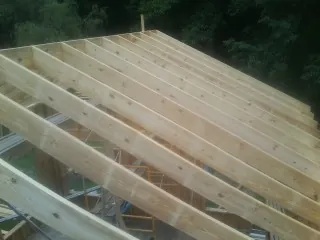 New roof rafters set over an addition before sheathing in Glenville